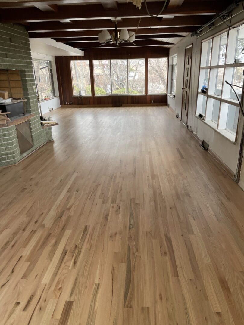 Spacious room with wooden floor and fireplace.