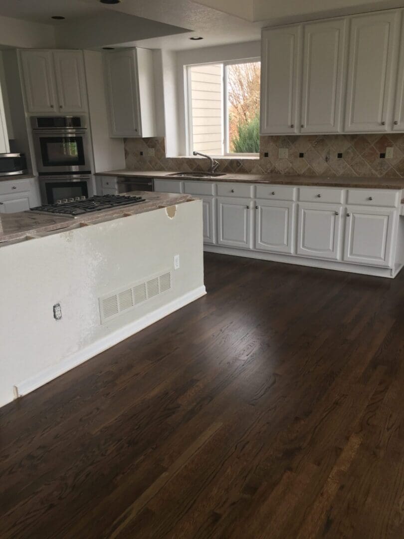 Modern kitchen with white cabinets and hardwood flooring.
