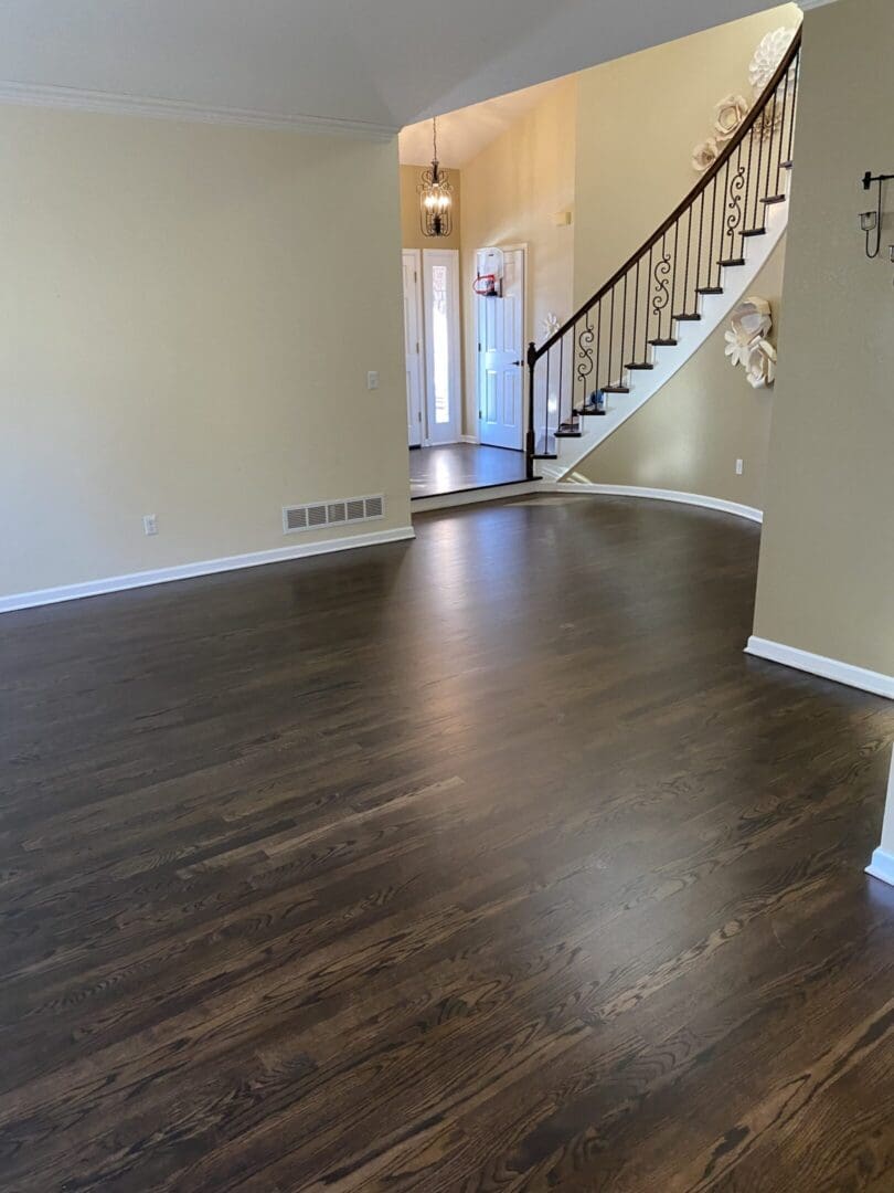 Spacious room with staircase and wooden floor.