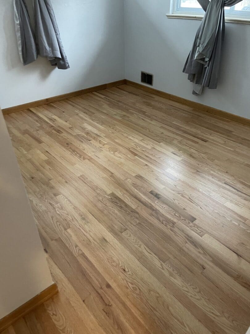 Empty room with wooden floor and curtains.