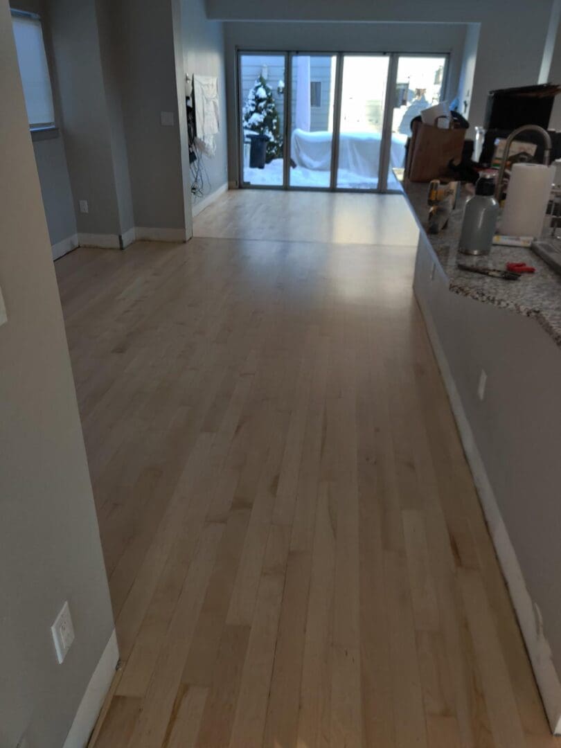 Spacious room with wooden floor and windows.